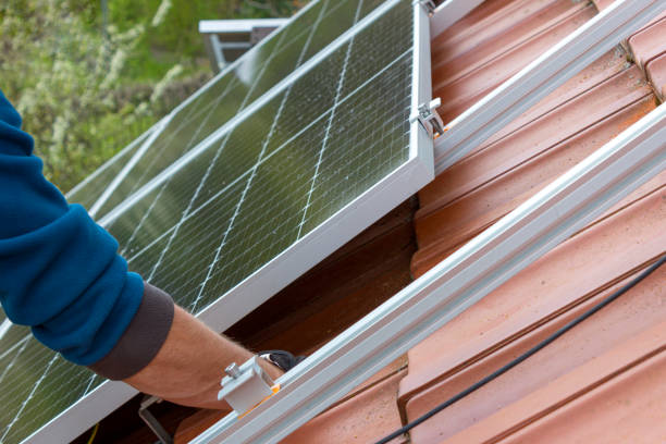 Worker installing solar panels on roof. Alternative energy concept.